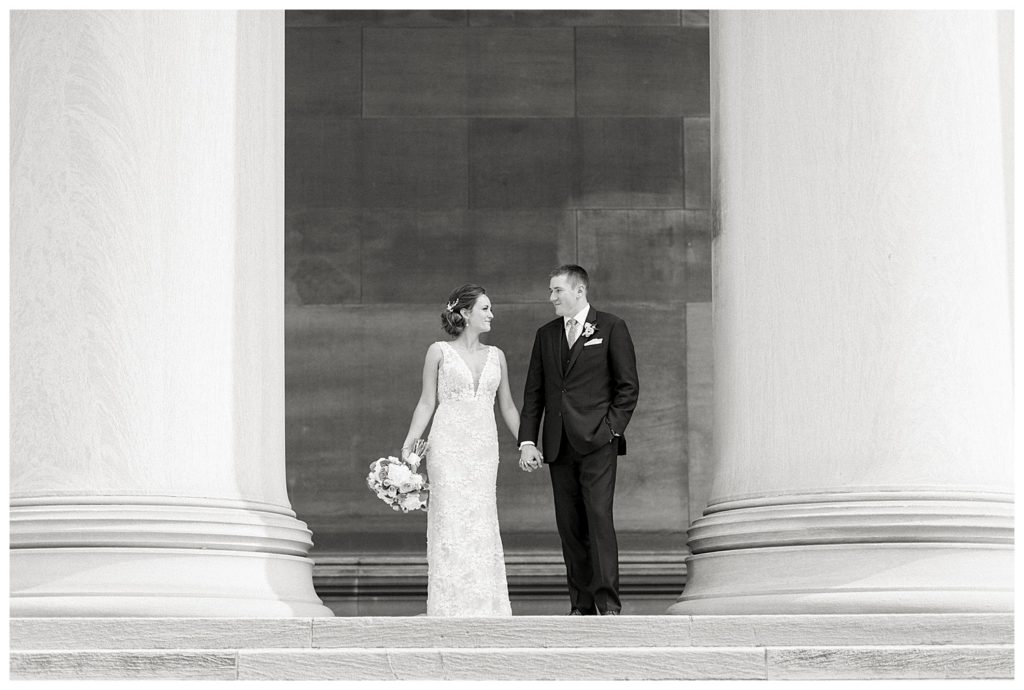 A bride and groom between two columns at Carnegie Library in Pittsburgh.